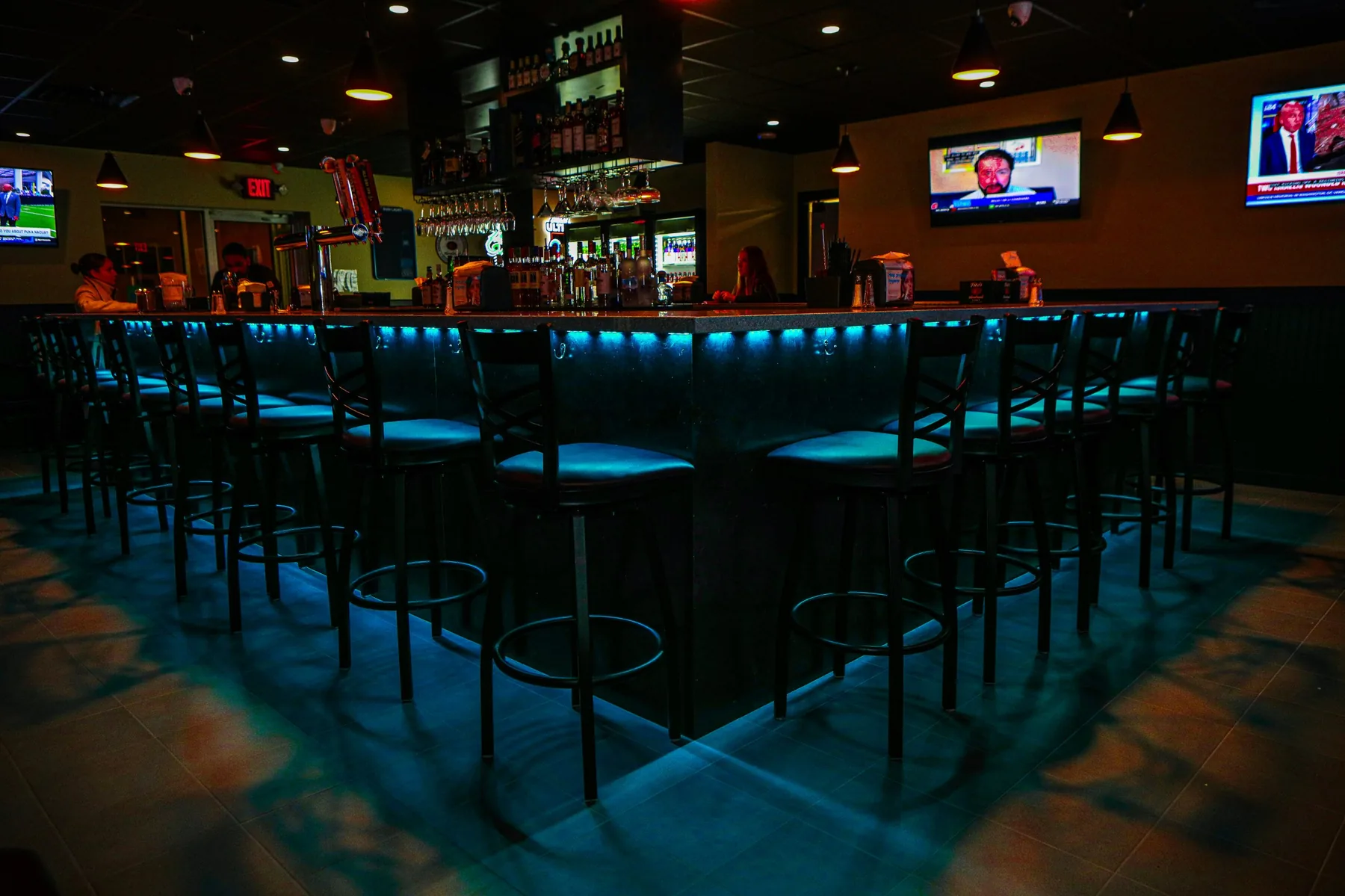 Bar interior with teal underglow lighting photographed for a nightlife brand