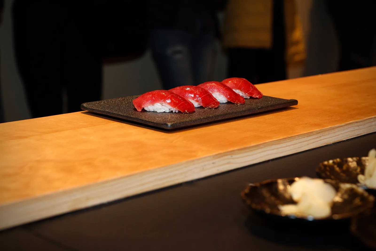 Tuna nigiri plated on a black stone dish at the omakase counter